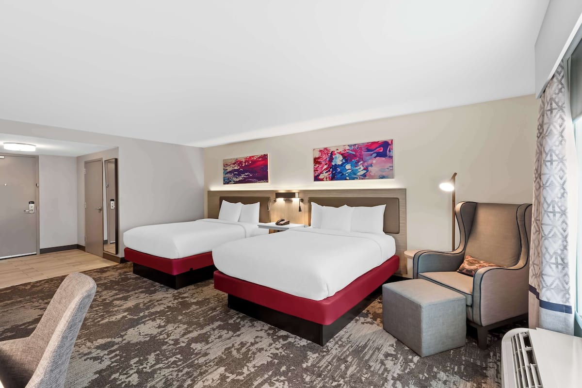 Habitación de hotel con dos camas, una silla, una mesita y un calefactor.