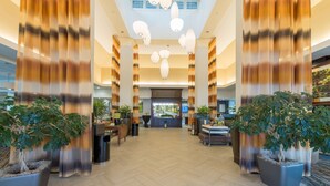 A spacious lobby with a herringbone floor pattern, large potted plants, and a reception desk in the center. - Hilton Garden Inn Atlanta Airport North (Atlanta)