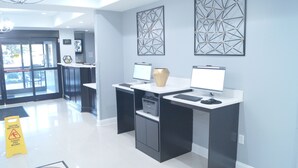 Un espace de bureau moderne avec deux bureaux, chacun équipé d’un ordinateur et d’un vase. Deux grandes œuvres d’art géométriques sont accrochées au mur au-dessus des bureaux.