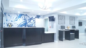 Un espace d’accueil moderne avec un comptoir noir, une œuvre d’art abstraite bleue au mur et un lustre.