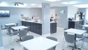 Un hall d’hôtel moderne avec un comptoir d’accueil, un espace salon et une cuisine visible au fond.