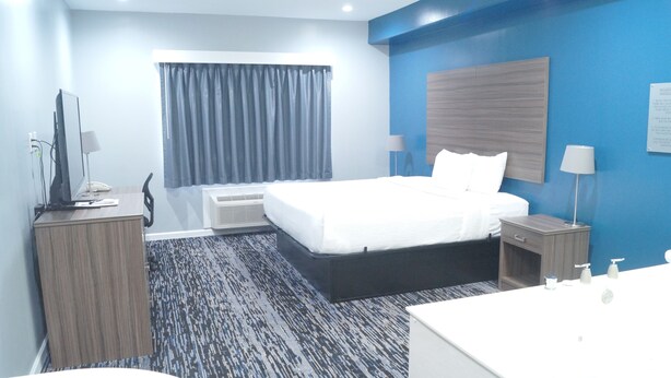 Une chambre d’hôtel équipée d’un lit, de tables de chevet, d’un bureau, d’une chaise, d’un téléviseur et d’un appareil de climatisation.