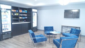Une pièce dotée d’un coin cuisine, de chaises recouvertes d’un tissu bleu, d’un téléviseur à écran plat et d’une grande fenêtre.