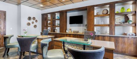 A modern kitchen with a bar area, wooden cabinets, and a flat-screen TV.