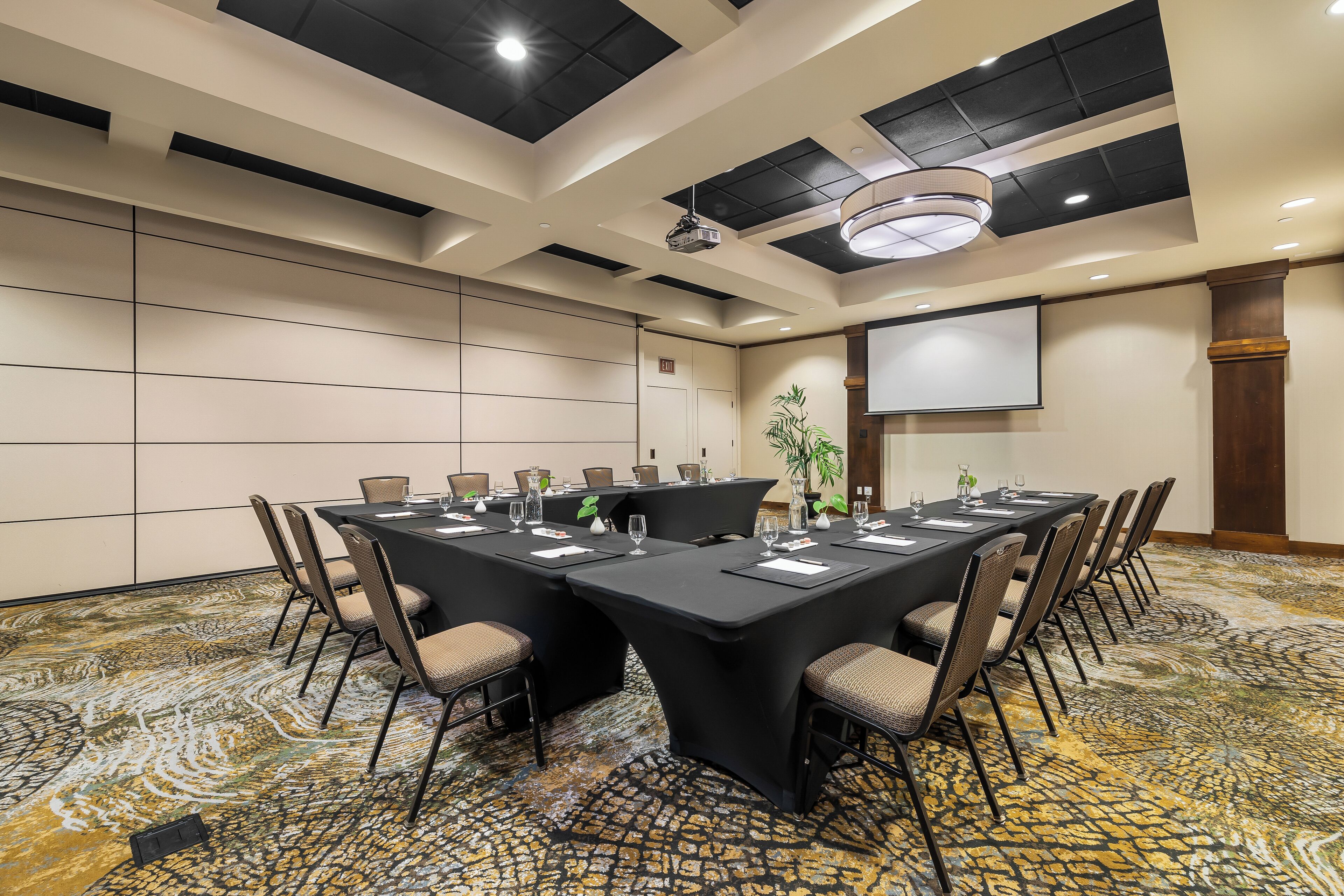 Une salle de conférence équipée d’une longue table, de chaises, d’un projecteur et d’un écran.