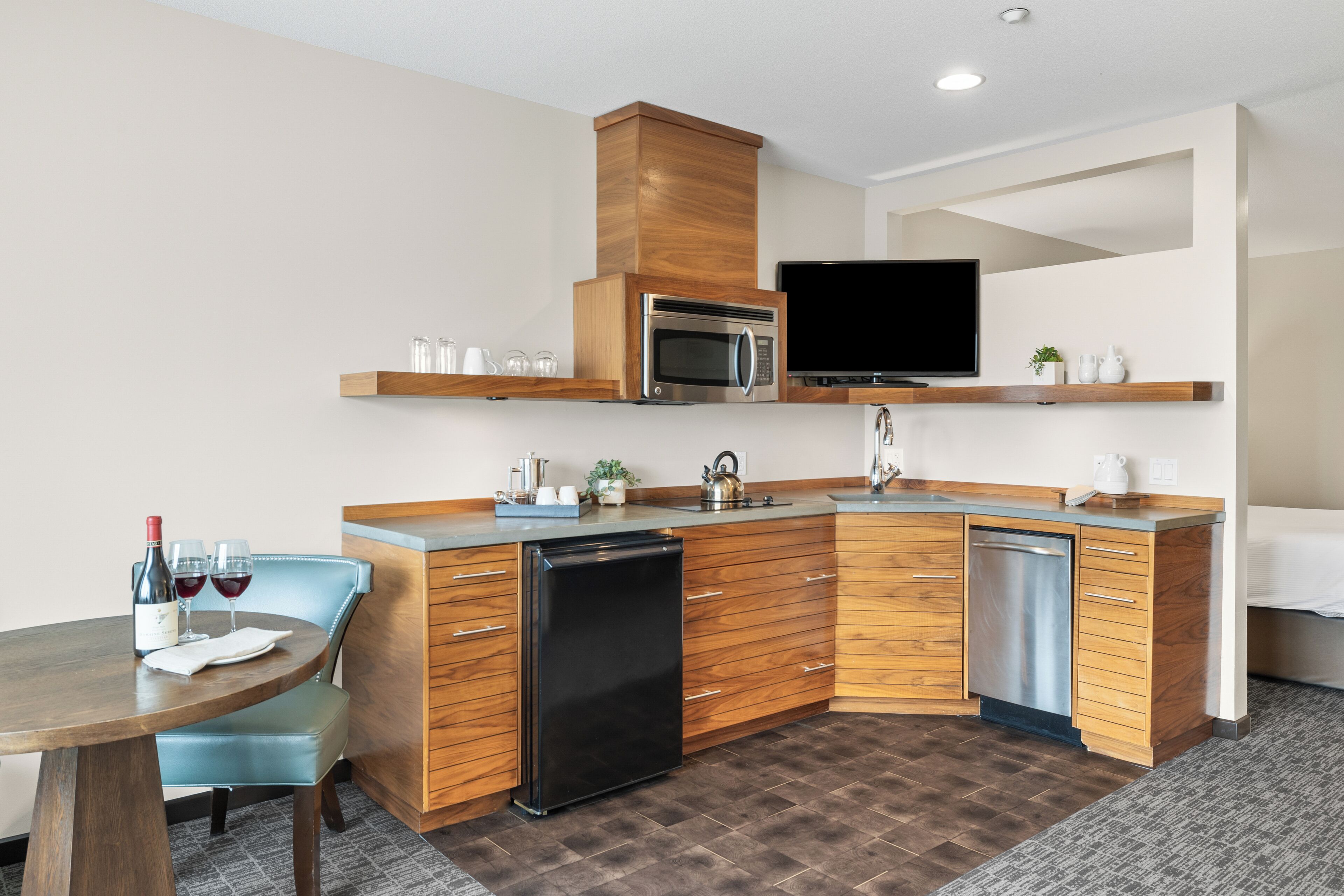 Una cocina moderna con un armario de madera, microondas, lavavajillas y un comedor con mesa y sillas.
