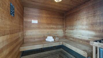 Eine Sauna mit Holzwänden und -bänken, inklusive Handtuchhalter und Heizung.