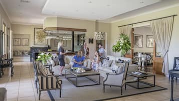A spacious living room with a large sofa, coffee table, and a dining area with a table and chairs.