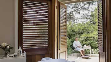 Relax in a serene spa room with a massage table, vanity, and outdoor views.