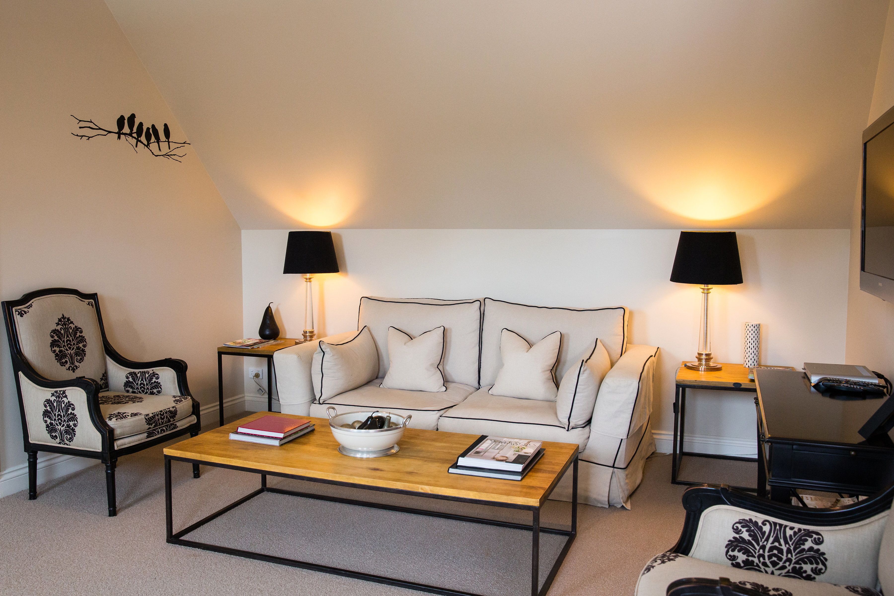 Un salon comprenant un canapé, deux fauteuils, une table basse et deux lampes.