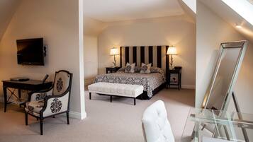 A bedroom with a bed, bedside tables, a desk, a chair, a TV, and a large mirror.