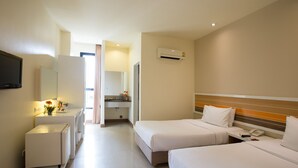 Quarto de hotel com duas camas, uma pequena mesa, um espelho e uma televisão.
