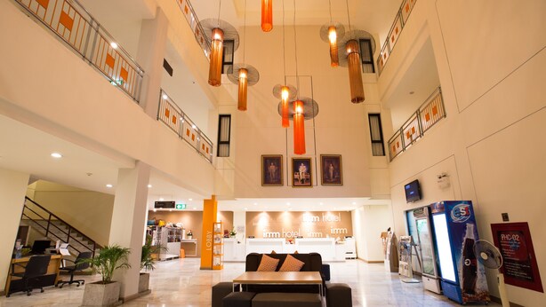 Um saguão de hotel com balcão de recepção, área de estar e escadaria.