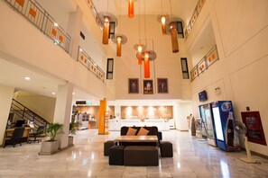 A hotel lobby with a reception desk, seating area, and a staircase.