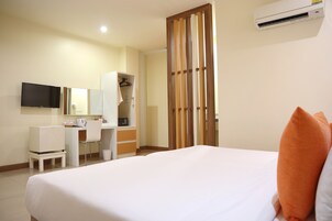 A hotel room with a bed, a desk, a chair, a TV, and a wardrobe.