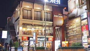 Um hotel com uma placa grande 'imm hotel', um McDonald's e uma entrada visível.