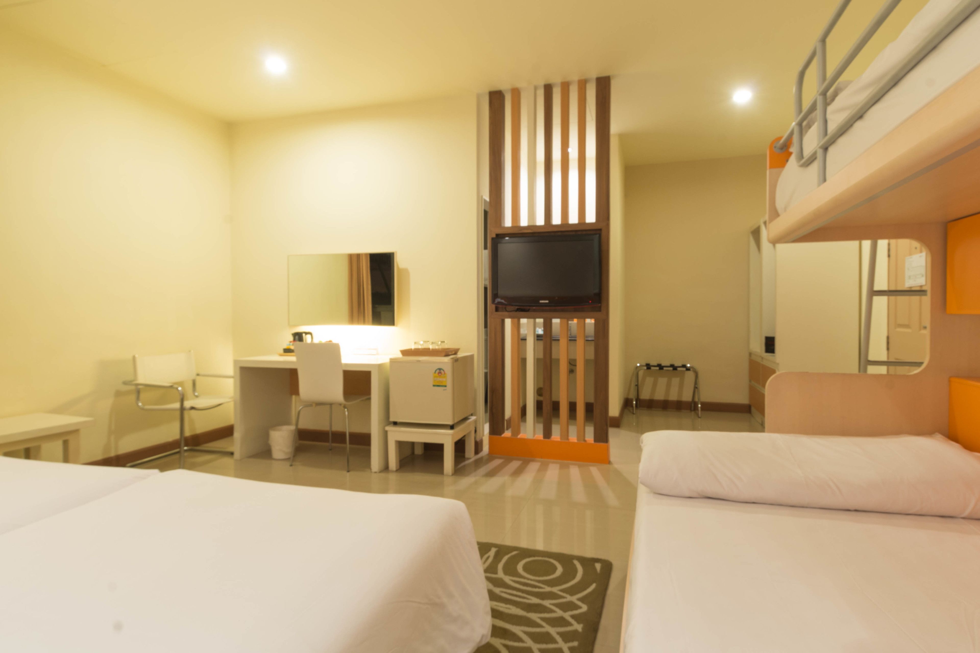 A hotel room with bunk beds, a desk, a chair, a television, and a mirror.