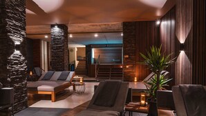 Ein moderner Lounge-Bereich mit einer Wand aus Stein, einem Sofa und einem Sessel.