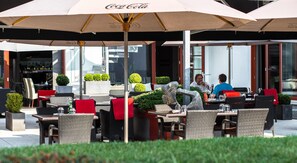An outdoor cafe with tables and chairs under umbrellas, some with Coca-Cola branding. - Volcano Spa Hotel (Prague)