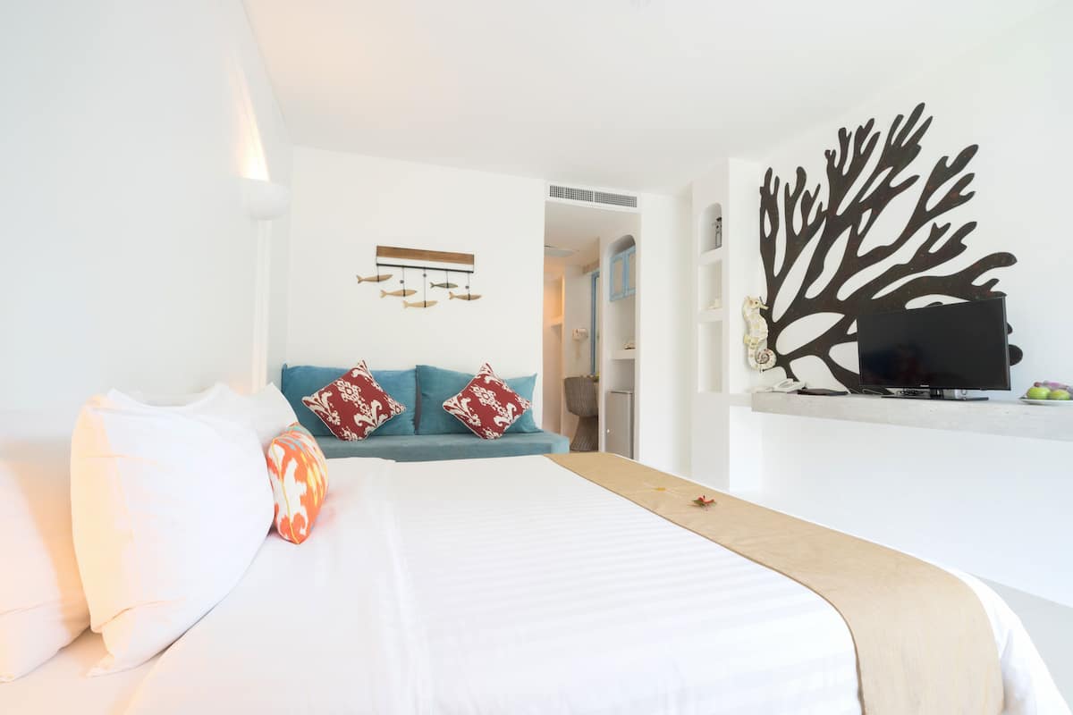 Een hotelkamer met een bed, een bank, een televisie en een decoratie aan de muur.