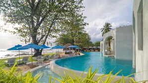 A pool area with lounge chairs and umbrellas, surrounded by greenery and architectural columns. - Ocean Breeze Resort Khao Lak (Takua Pa)