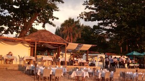 A beachside restaurant with outdoor seating, tables, and umbrellas. - Ocean Breeze Resort Khao Lak (Takua Pa)