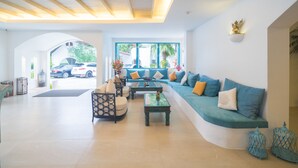 A modern living room with a curved sofa, a coffee table, and a patterned armchair. - Ocean Breeze Resort Khao Lak (Takua Pa)