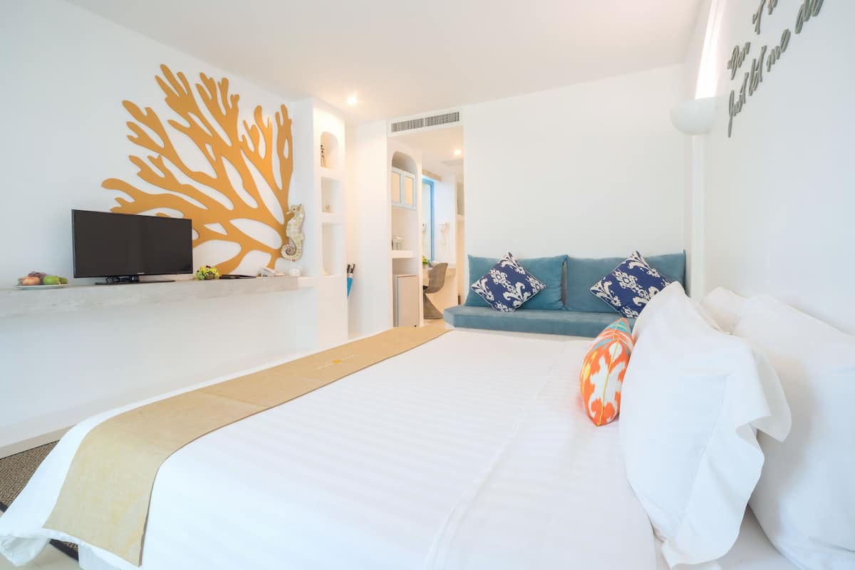 Een moderne hotelkamer met een bed, een televisie, een bank en een decoratief wandobject.