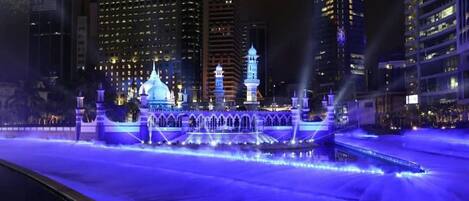 A nighttime view of a hotel with illuminated water features and a prominent dome structure.