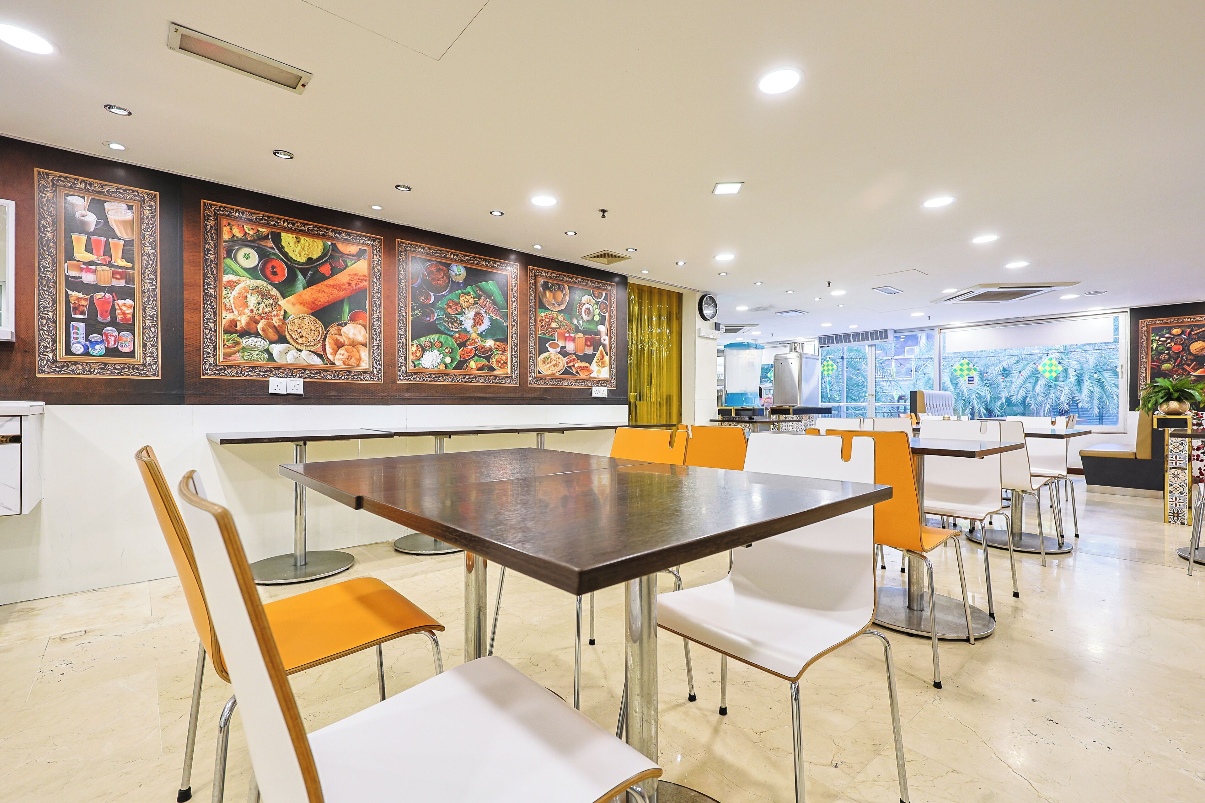 A dining area with tables and chairs, a clock on the wall, and artwork depicting food.
