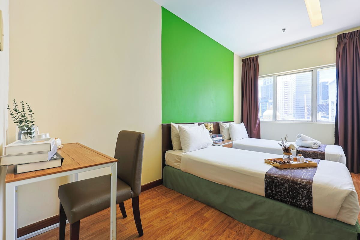 Une chambre d’hôtel avec deux lits, un bureau et une chaise.