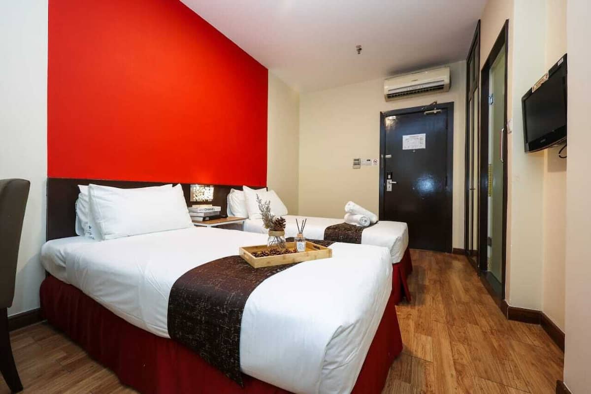 Une chambre d’hôtel avec un grand lit, un plus petit lit, une télévision et une porte avec une pancarte.