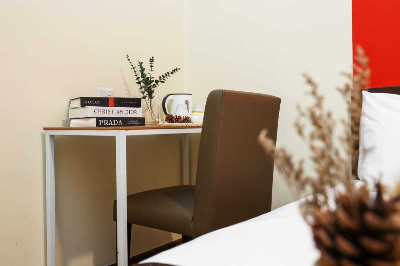 A neatly arranged desk with a stack of books, a coffee pot, and a small plant.