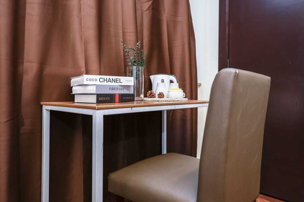 A small table with a stack of books, a white teapot, and a small plant.
