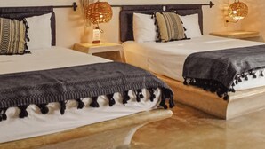 Una habitació d'hotel amb dos llits, un penjador de plomes i una làmpada fixada a la paret.