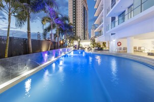 Una piscina al aire libre, sombrillas, sillones reclinables de piscina