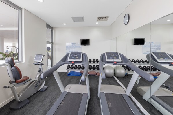 Un gimnasio con cintas de correr, mancuernas y equipamiento de ejercicio.