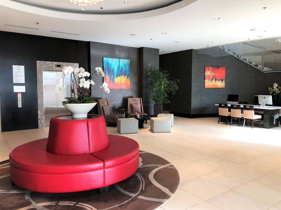 A modern lobby with a red seating area, a reception desk, and a staircase.