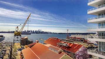 A waterfront property with a crane, a city skyline in the background, and a large mural on the building.