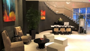 A modern lobby with a reception desk, seating area, staircase, and artwork on the walls. - Pinnacle Hotel at the Pier (North Vancouver)