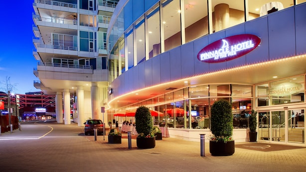 A hotel with a modern design, featuring a prominent sign, large windows, and outdoor seating areas. - Pinnacle Hotel at the Pier (North Vancouver)