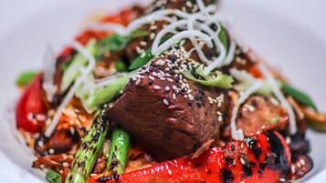 A plate of food with grilled vegetables and meat, garnished with sesame seeds.