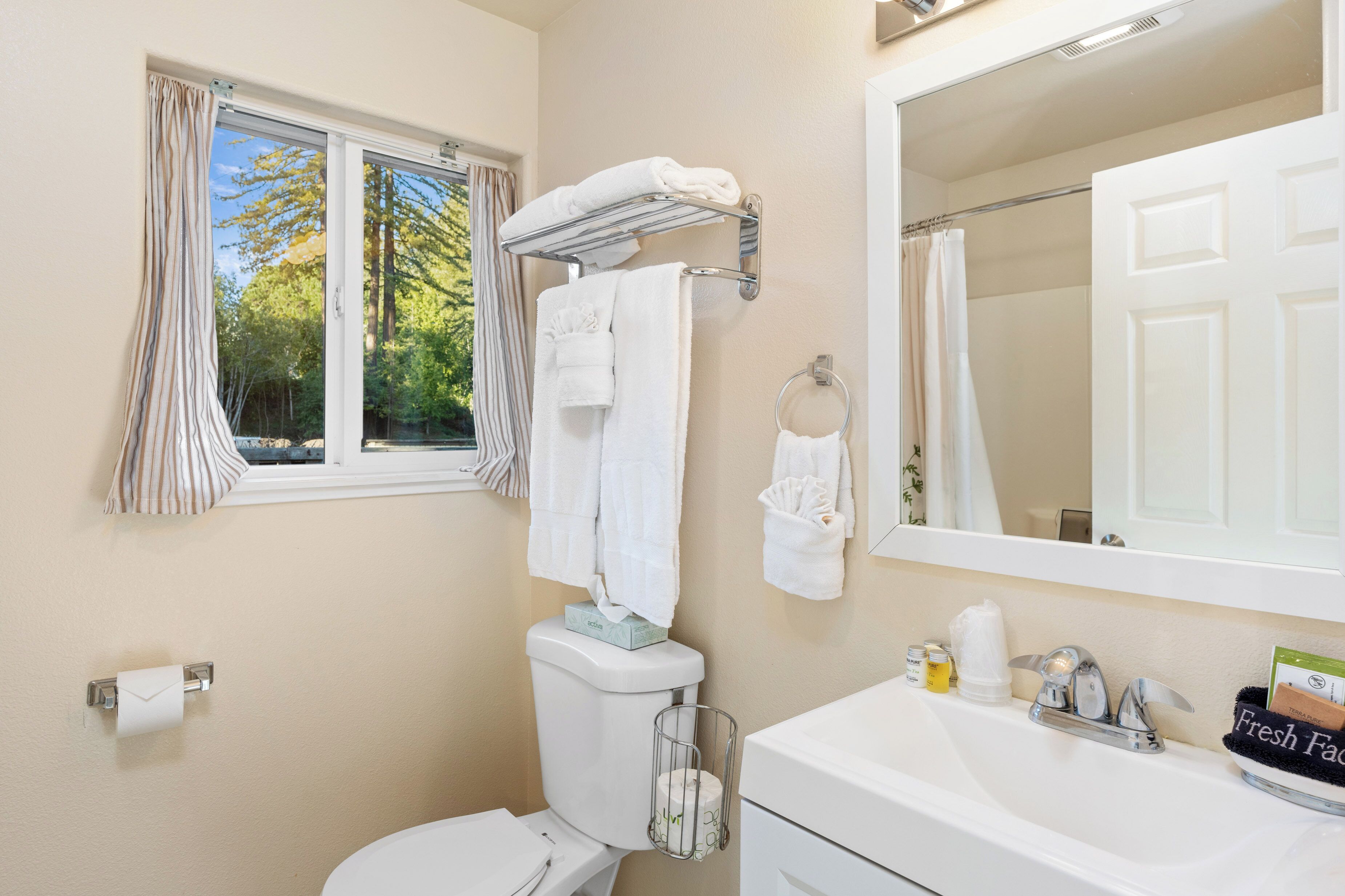 Un baño con inodoro, lavabo y ventana con cortinas.