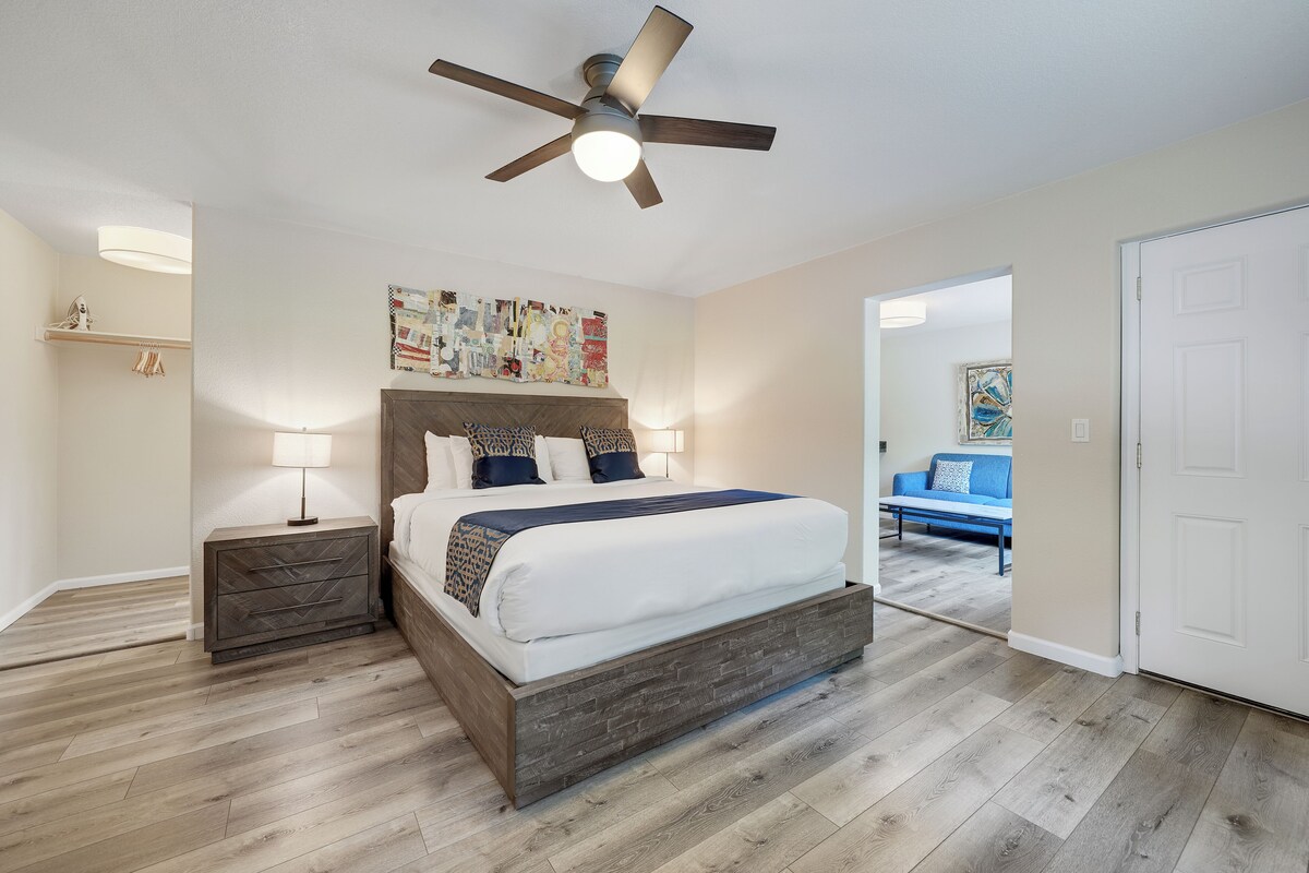 A bedroom with a bed, bedside tables, a ceiling fan, and a wall art piece.