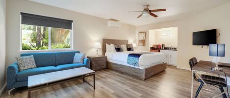 Quarto de hotel moderno com sofá, cama, escrivaninha e televisão.
