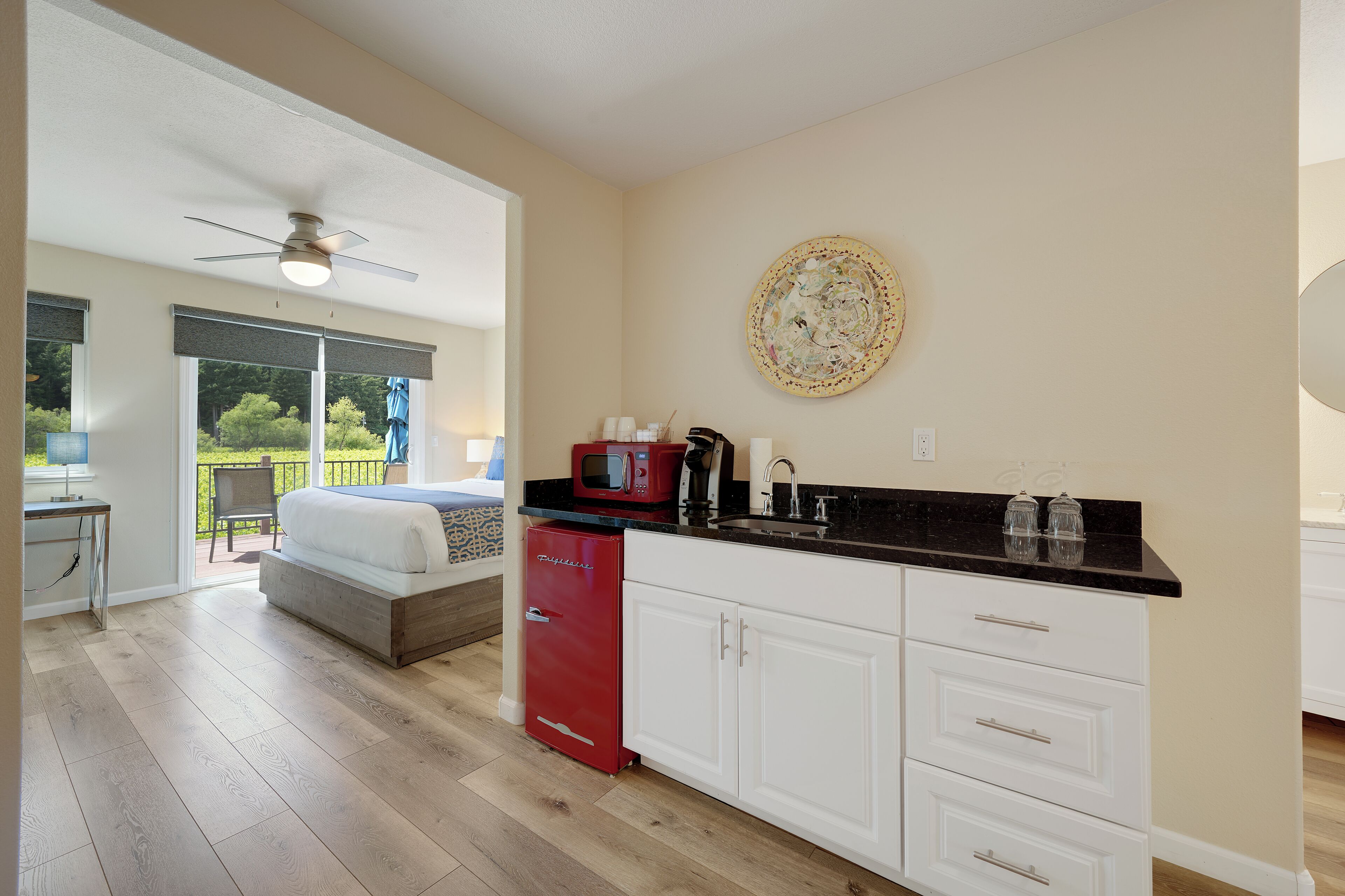 A modern kitchen with a red refrigerator, white cabinets, and a black countertop.