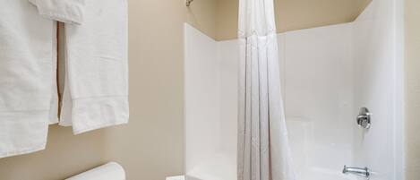 A bathroom with a bathtub, a shower curtain, and a toilet.