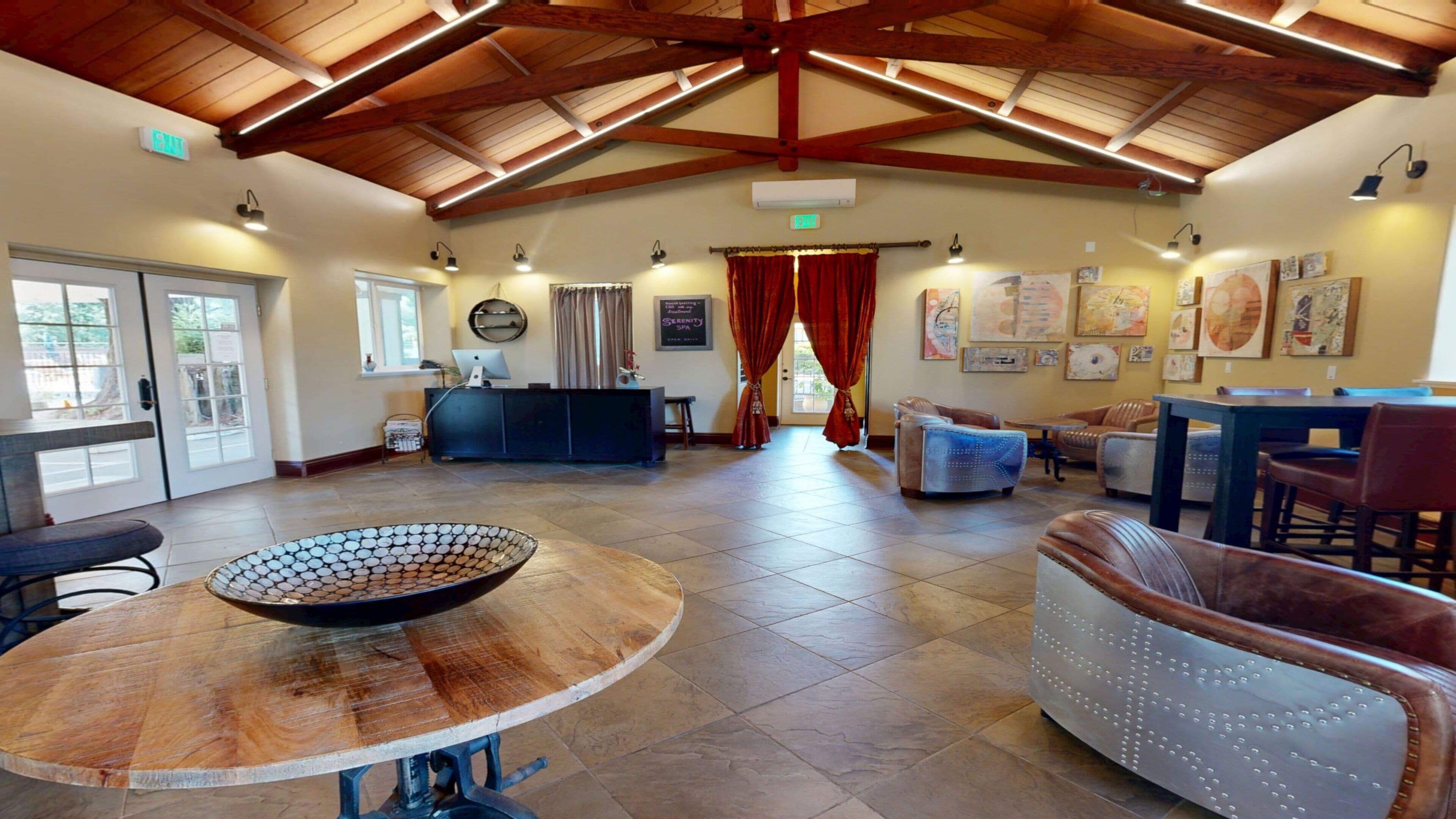 A spacious lobby with a high ceiling, a reception desk, seating area, and artwork on the walls.