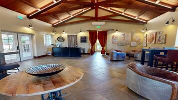 A spacious lobby with a high ceiling, a reception desk, seating area, and artwork on the walls.