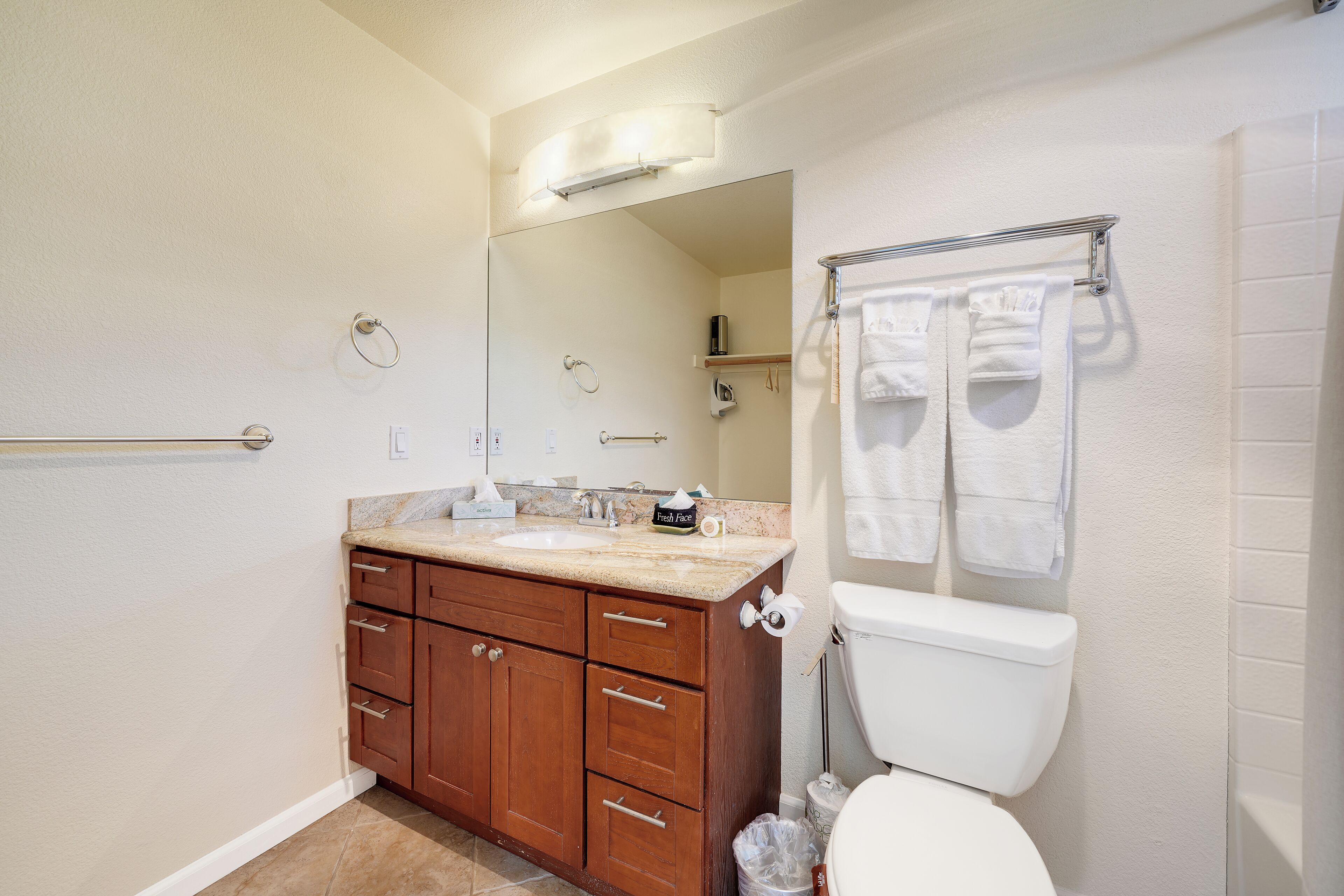 A bathroom with a toilet, sink, wooden vanity, towel rack, and a mirror.